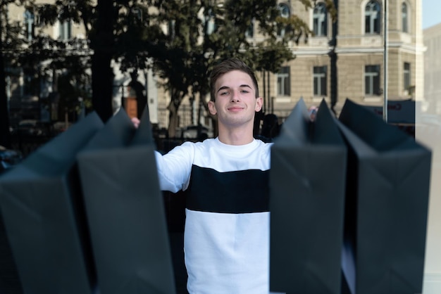 Ragazzo con la borsa della spesa nera sullo sfondo della città Mens shopping Sale