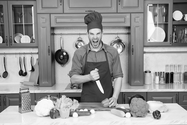 Ragazzo con la faccia arrabbiata con verdure tagliate a coltello