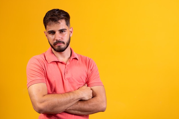 Ragazzo con le braccia incrociate sorridente su sfondo giallo con spazio libero.