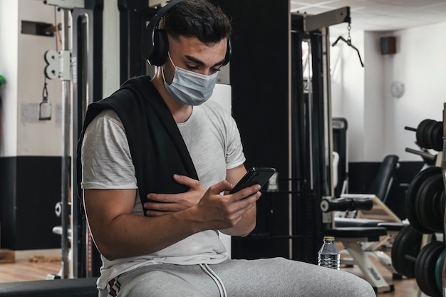 Ragazzo con maschera che impara con l'uso dello smartphone in palestra