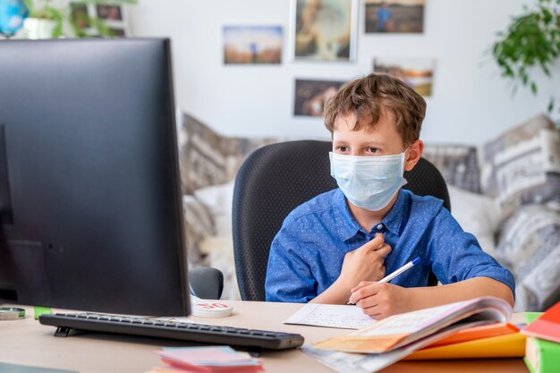 Ragazzo con maschera protettiva a fare i compiti