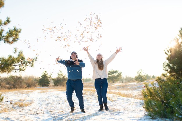 ragazzo con ragazza lanciare coriandoli nella foresta invernale