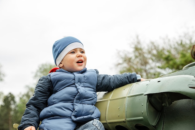 Ragazzo contro il cielo limpido bambino esplora il vecchio carro armato militare d'epoca