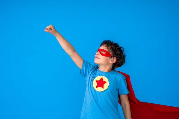 Ragazzo coraggioso in costume da supereroe con mantello rosso e maschera tese la mano