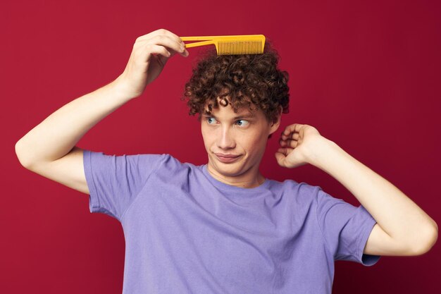 Ragazzo dai capelli rossi carino in magliette viola con un pettine isolato sullo sfondo