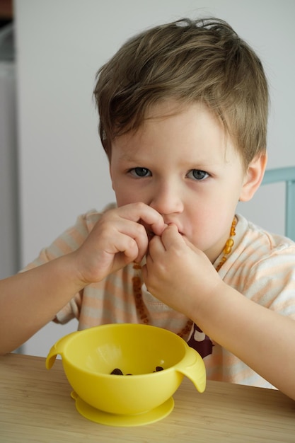 Ragazzo del bambino che mangia felicemente dal tavolo a casa