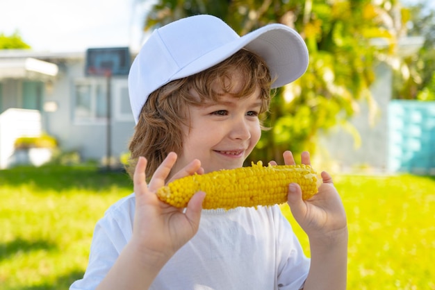 Ragazzo del bambino che si diverte con il bambino del mais delle verdure del cibo nel ragazzo adorabile del mais del giardino che mangia il mais sul