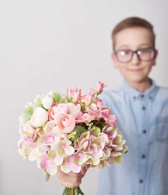 Ragazzo del bambino con il mazzo di fiori. Cartolina d'auguri festa della mamma. Felice festa della mamma cornice di sfondo.