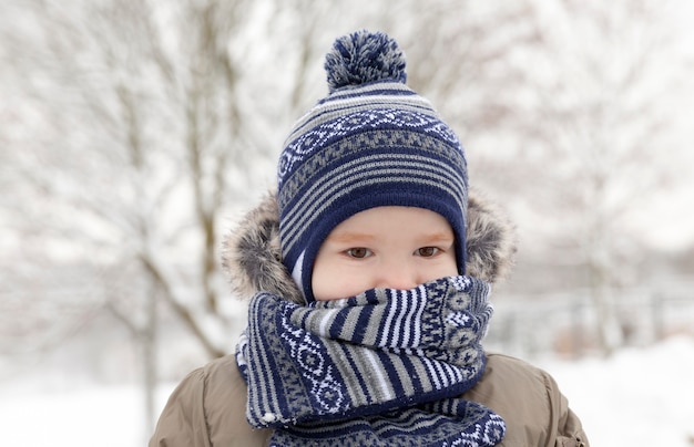 Ragazzo del bambino in giovane età mentre si cammina lungo la strada, primo piano in inverno