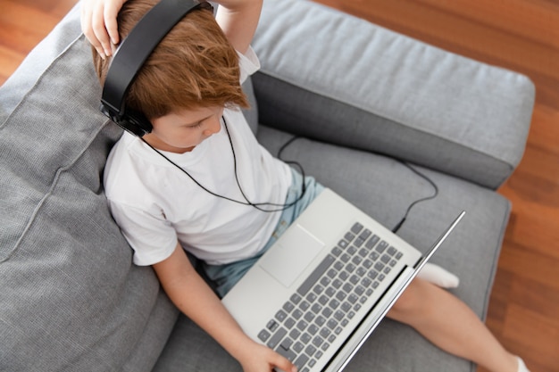 Ragazzo del bambino utilizzando laptop e cuffie per l'istruzione in linea