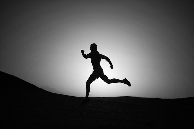 Ragazzo del corridore della siluetta o dell'uomo che corre all'aperto al cielo sereno