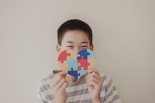 Ragazzo del preteen che tiene puzzle jigsaw, salute mentale del bambino, giornata mondiale della consapevolezza dell'autismo