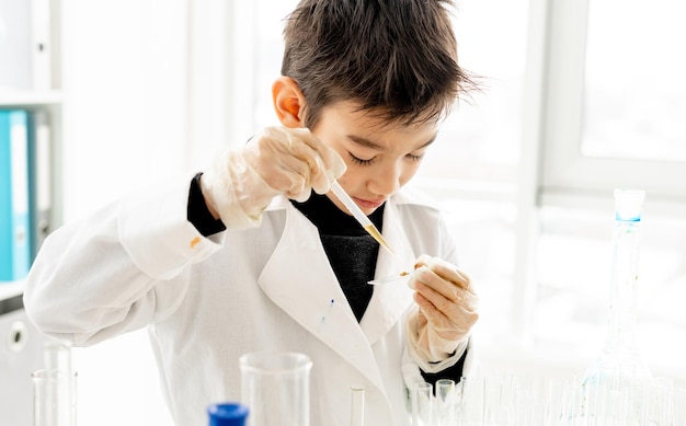 Ragazzo della scuola che misura i componenti durante l'esperimento di chimica nella classe di scienze elementari Bambino intelligente in laboratorio