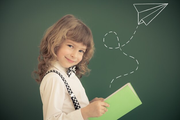 Ragazzo della scuola in classe. Bambino felice contro la lavagna verde. Concetto di educazione