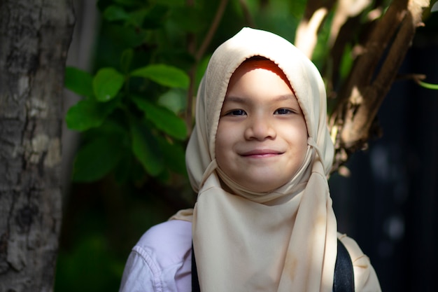 Ragazzo della scuola musulmana. Bambina graziosa nel hijab facendo uso della macchina fotografica digitale.