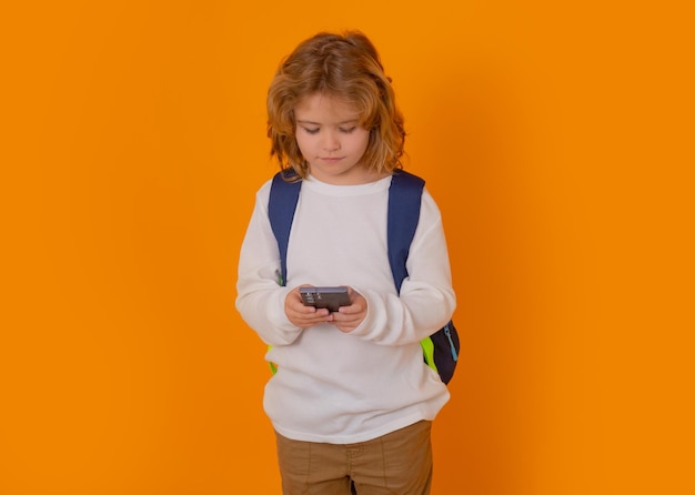 Ragazzo della scuola utilizzando il telefono isolato su sfondo giallo studio isolato