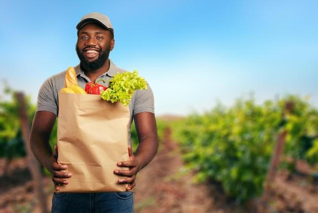 Ragazzo delle consegne con un sacchetto della spesa pieno di cibo con l'orto da cui arrivano i prodotti