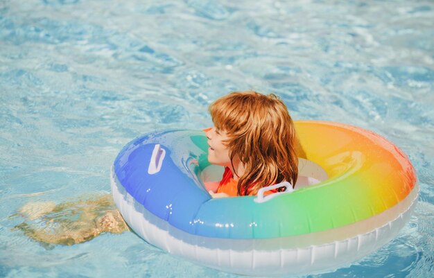 Ragazzo delle vacanze estive in piscina bambino all'aquapark ragazzo divertente sul cerchio di gomma gonfiabile