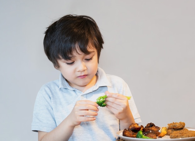 Ragazzo di 7 anni con pepite di pollo fatte in casa e patate arrosto e broccoli