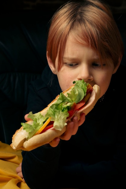 Ragazzo di 9 anni che mangia un grande panino con la baguette