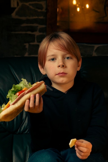 Ragazzo di 9 anni che mangia un grande panino con la baguette