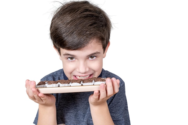 Ragazzo di 9 anni che mostra i suoi denti e tiene in mano un vassoio con diverse palline di fondente brasiliane