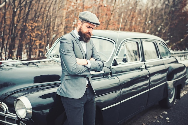 Ragazzo di chiamata in auto d'epoca Uomo barbuto in auto Accompagnatore o guardia di sicurezza Auto da collezione retrò e riparazione auto da parte di autista meccanico Viaggi e viaggi d'affari o escursionismo con l'autostop