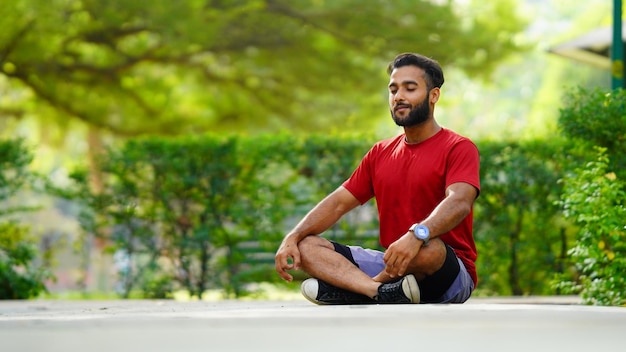 Ragazzo di immagine della giornata internazionale dello yoga che medita nella posizione del loto al parco