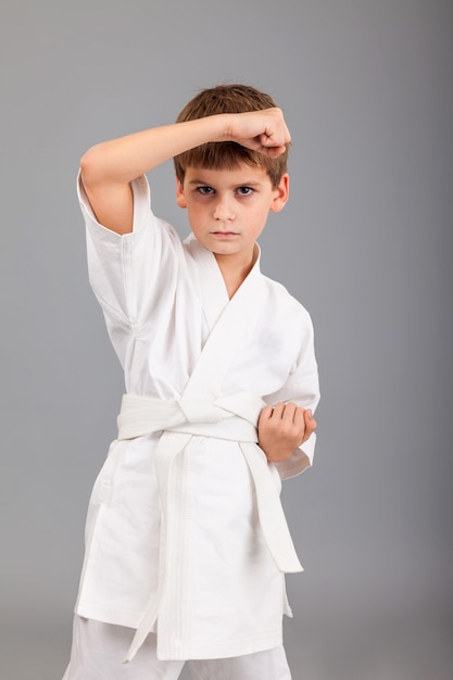 Ragazzo di karate in kimono bianco su sfondo grigio