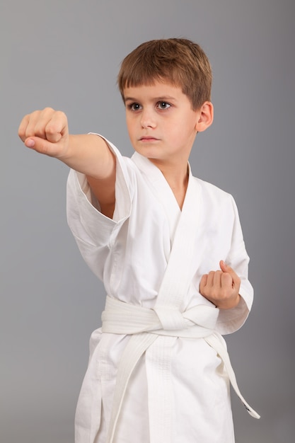 Ragazzo di karate in kimono bianco su sfondo grigio