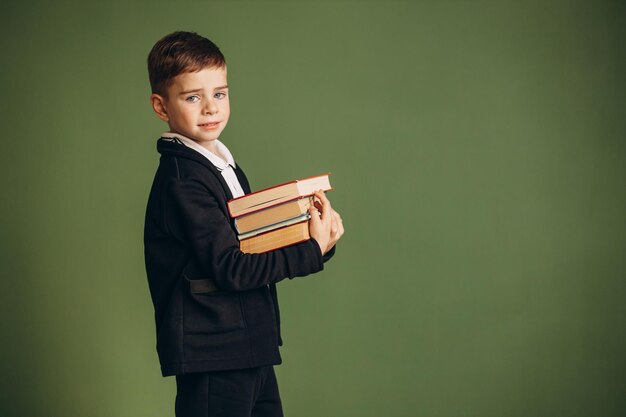 Ragazzo di scuola carino che indossa l'uniforme scolastica e tiene i libri