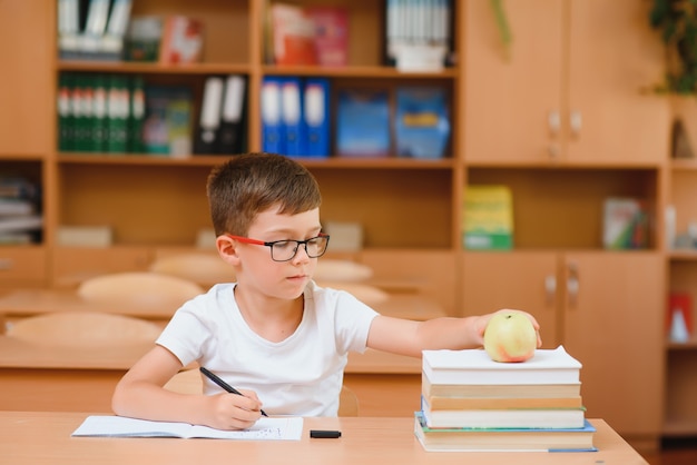 Ragazzo di scuola elementare alla scrivania dell'aula cercando di trovare nuove idee per i compiti.