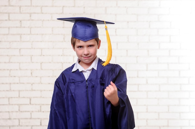 Ragazzo di scuola elementare in tazza e abito in posa con il diploma.