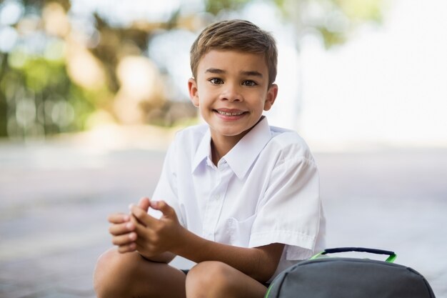 Ragazzo di scuola felice che si siede nel campus