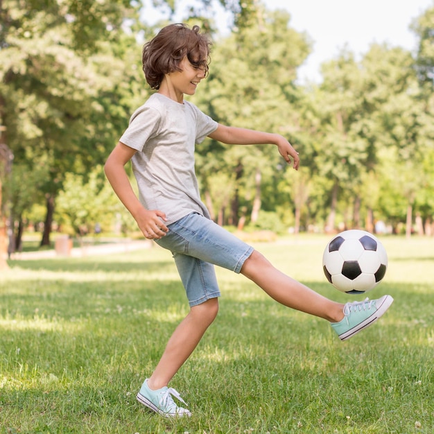 Ragazzo di vista laterale che gioca con la palla di calcio