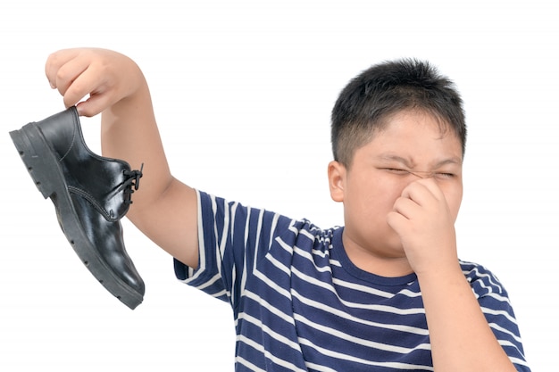 Ragazzo disgustato in possesso di un paio di scarpe in pelle puzzolente