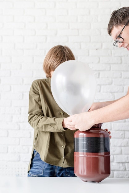 Ragazzo divertente che fa saltare in aria un palloncino con l'elio