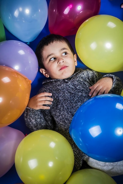 Ragazzo divertente che gioca con palloncini di molti colori