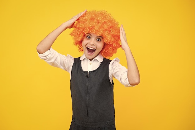 Ragazzo divertente con parrucca rossa riccia È ora di divertirsi Ragazza teenager con i capelli arancioni che è un clown Faccia sorpresa emozioni a sorpresa di una ragazza adolescente