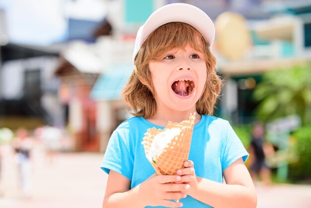 Ragazzo dolce del bambino che mangia il gelato sopra fondo con bokeh vago