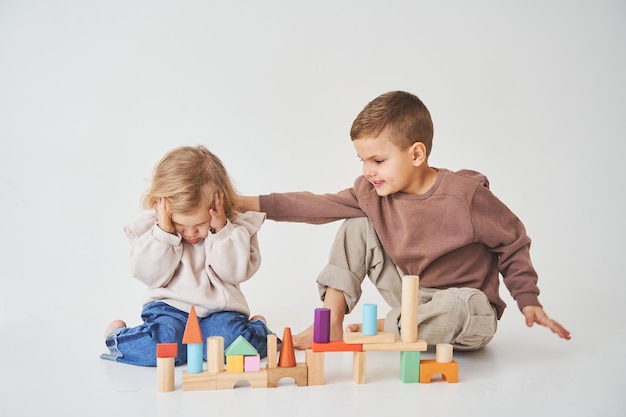 Ragazzo e bambina sorridente divertendosi e giocando giocattolo di mattoni colorati su sfondo bianco I bambini hanno sorridere e divertirsi insieme