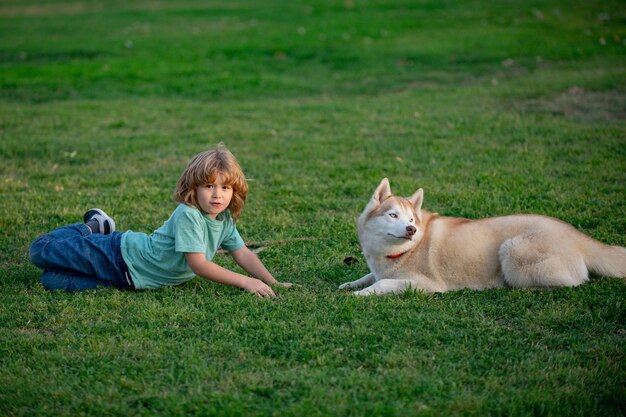 Ragazzo e cane sdraiati sull'erba insieme giochi divertenti con cane husky durante le vacanze estive