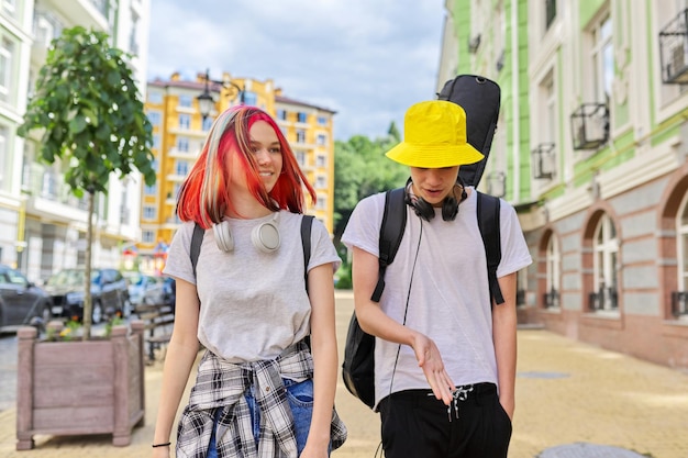 Ragazzo e ragazza alla moda hipsters che camminano parlando sulla strada della città ragazzo con la chitarra in caso Concetto di amicizia di comunicazione di creatività di stile di vita giovanile