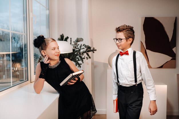 Ragazzo e ragazza alla moda stanno vicino alla finestra con i libri in mano.