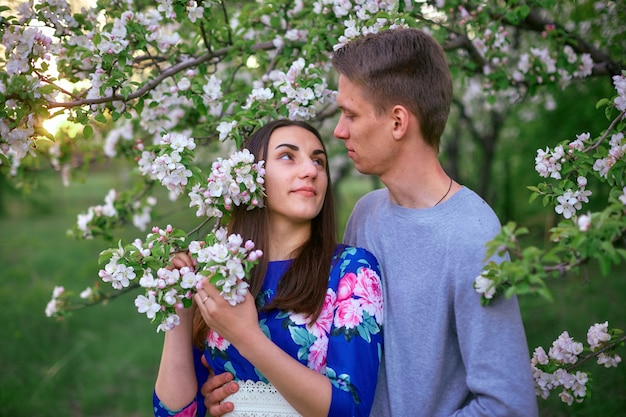 Ragazzo e ragazza amorosi in un meleto di fioritura al tramonto