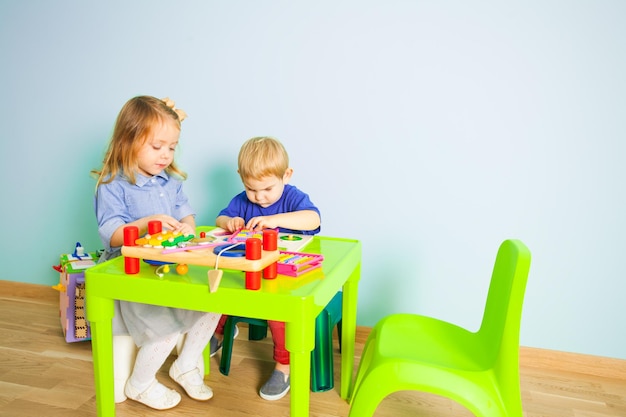 Ragazzo e ragazza che giocano al tavolo nella scuola materna nella classe prescolare Montessori.