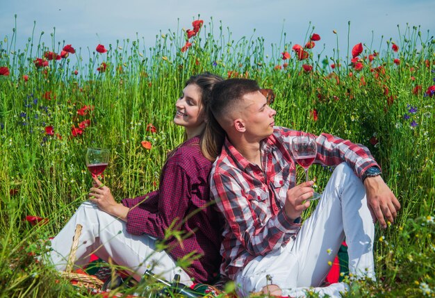 ragazzo e ragazza che hanno un appuntamento romantico nel campo di fiori di papavero con musica per chitarra e vino, appuntamento.