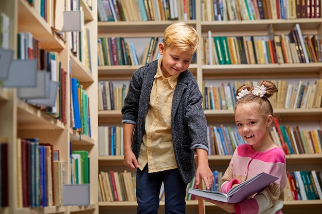 ragazzo e ragazza che parlano di libro in biblioteca scolastica, stili di vita di persone e amico Concetto di educazione e amicizia. tempo libero per bambini, attività di gruppo