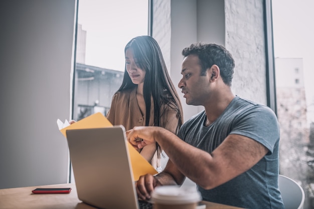 Ragazzo e ragazza con documenti vicino al laptop