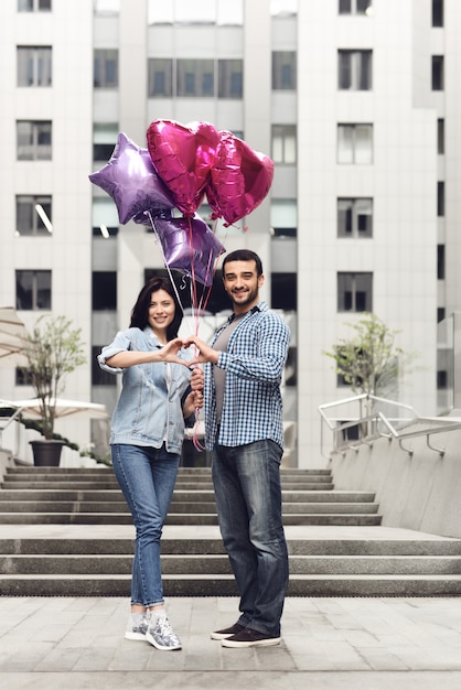 Ragazzo e ragazza con palloncini a forma di cuore mani.